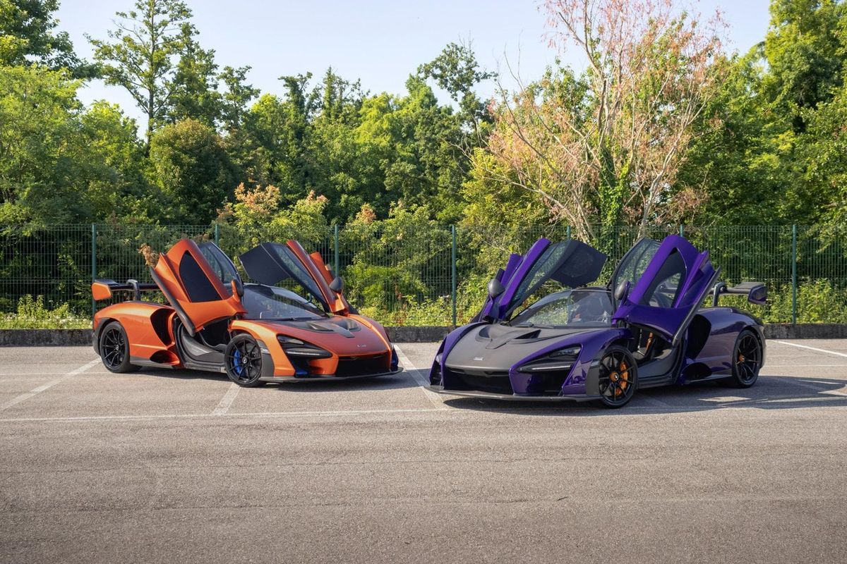 Due McLaren Senna con le porte aperte, una viola e una arancione, sul piazzale