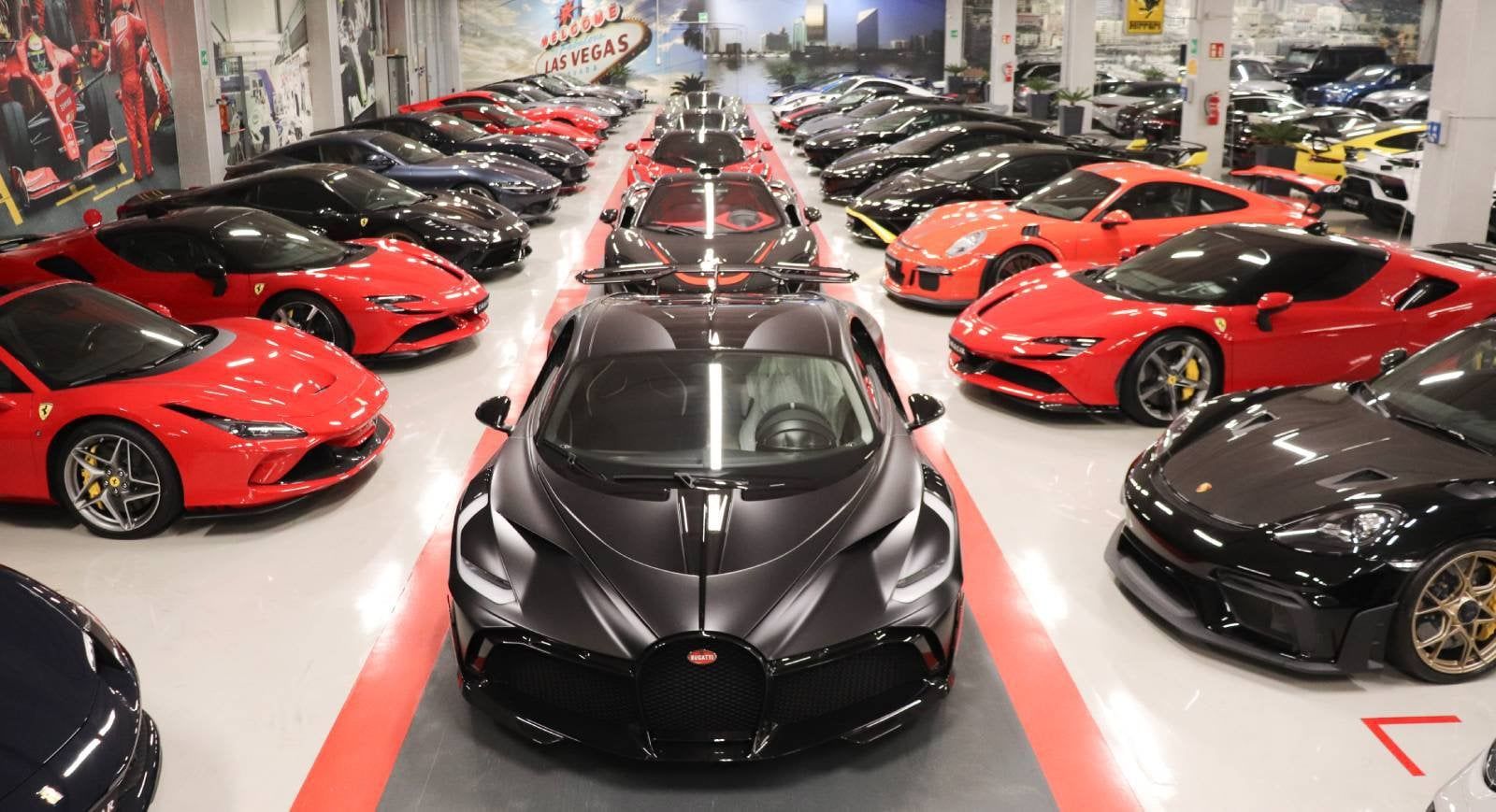 Il salone di Car & Car: file di supercar rosse e nere sul pavimento bianco con le strisce rosse
